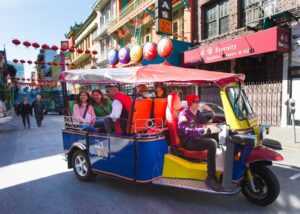 Passengers enjoying a private guided city tour riding in a colorful Lucky Tuk Tuk through San Francisco’s Chinatown.
